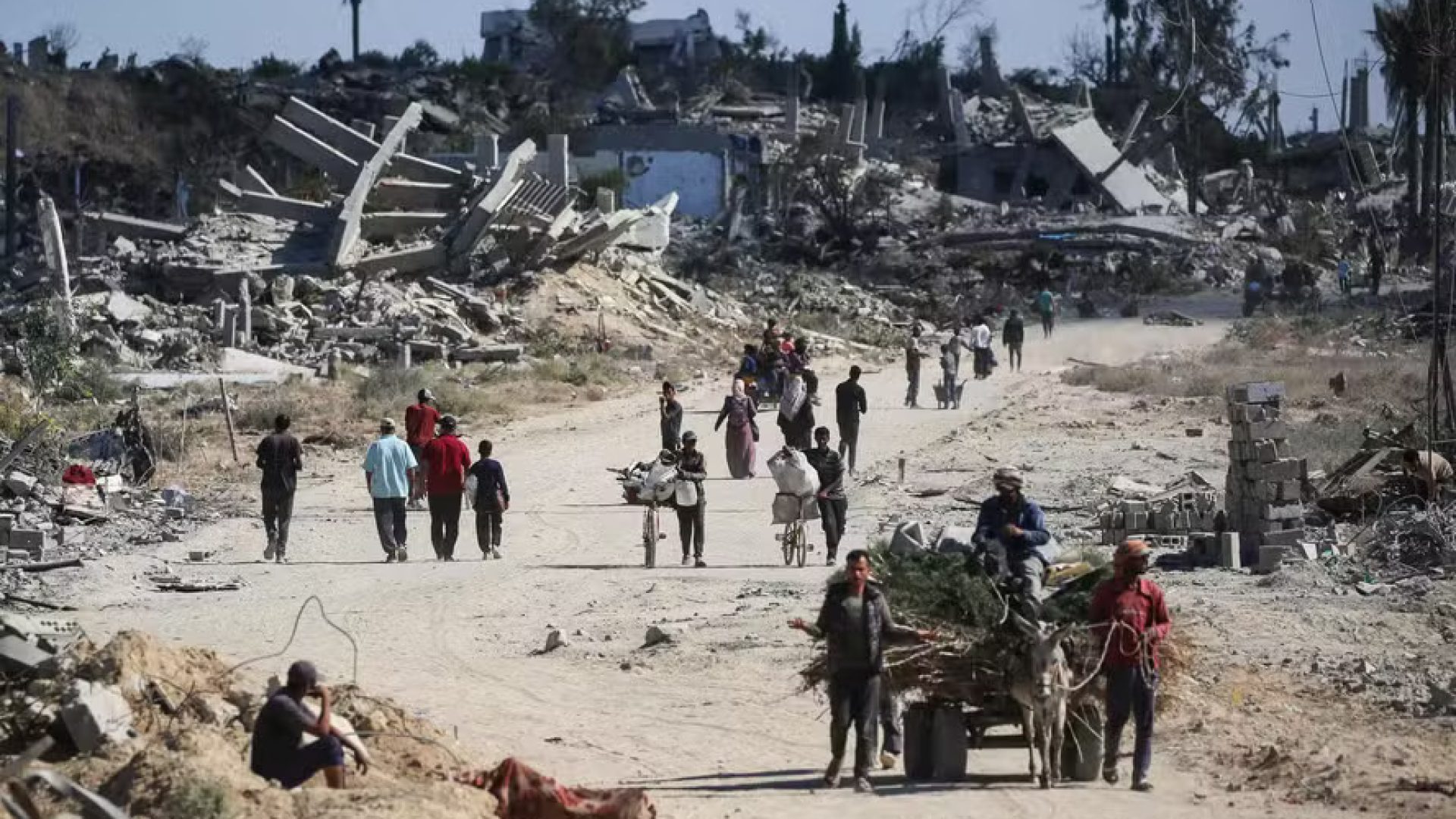 112692580-topshot-displaced-palestinians-walk-past-destroyed-buildings-as-they-return-to-their-hom.j.jpeg