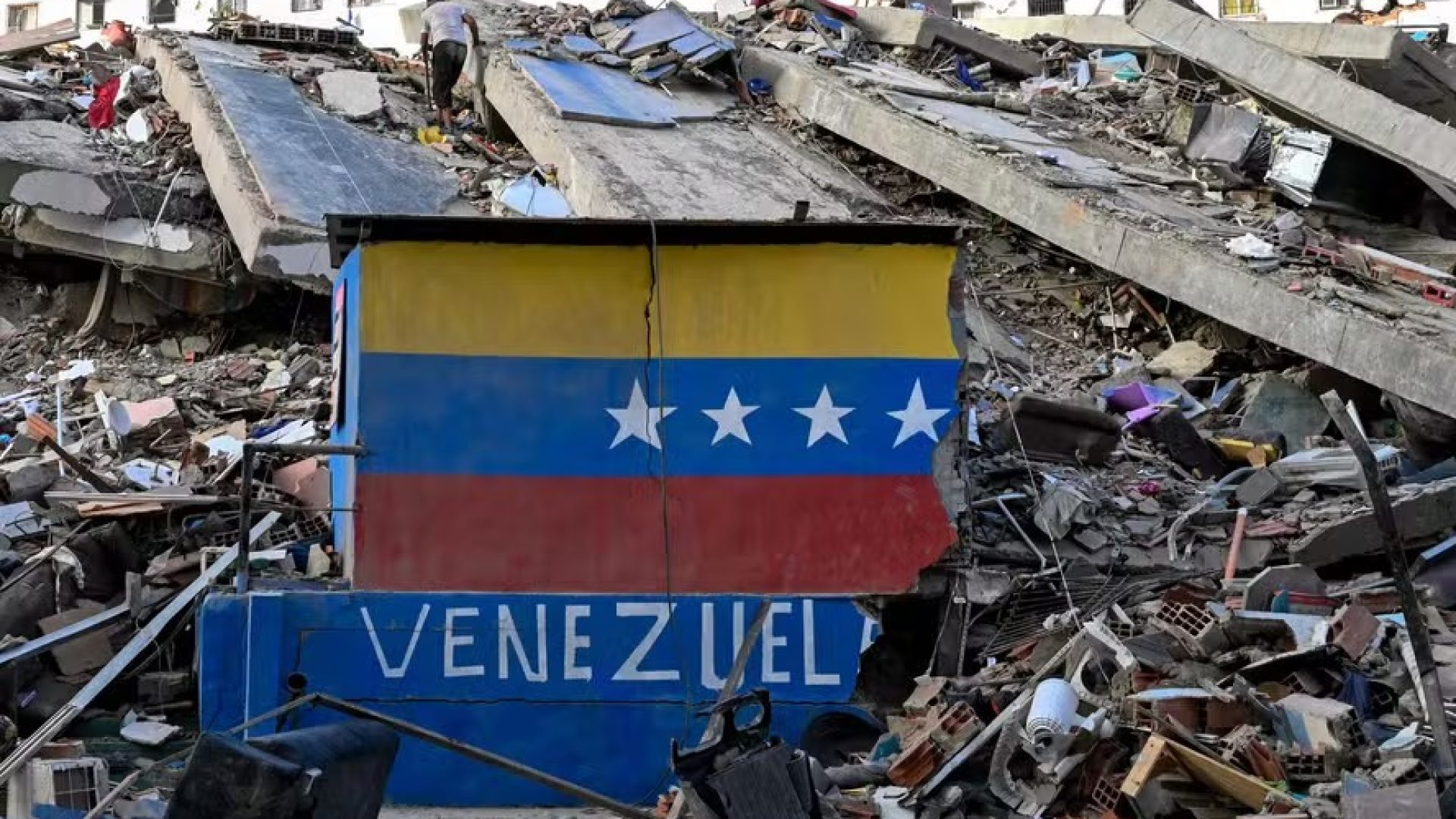 115455424-a-venezuelan-flag-is-seen-painted-on-a-damaged-wall-amid-the-rubble-of-a-collapsed-buildin.jpeg