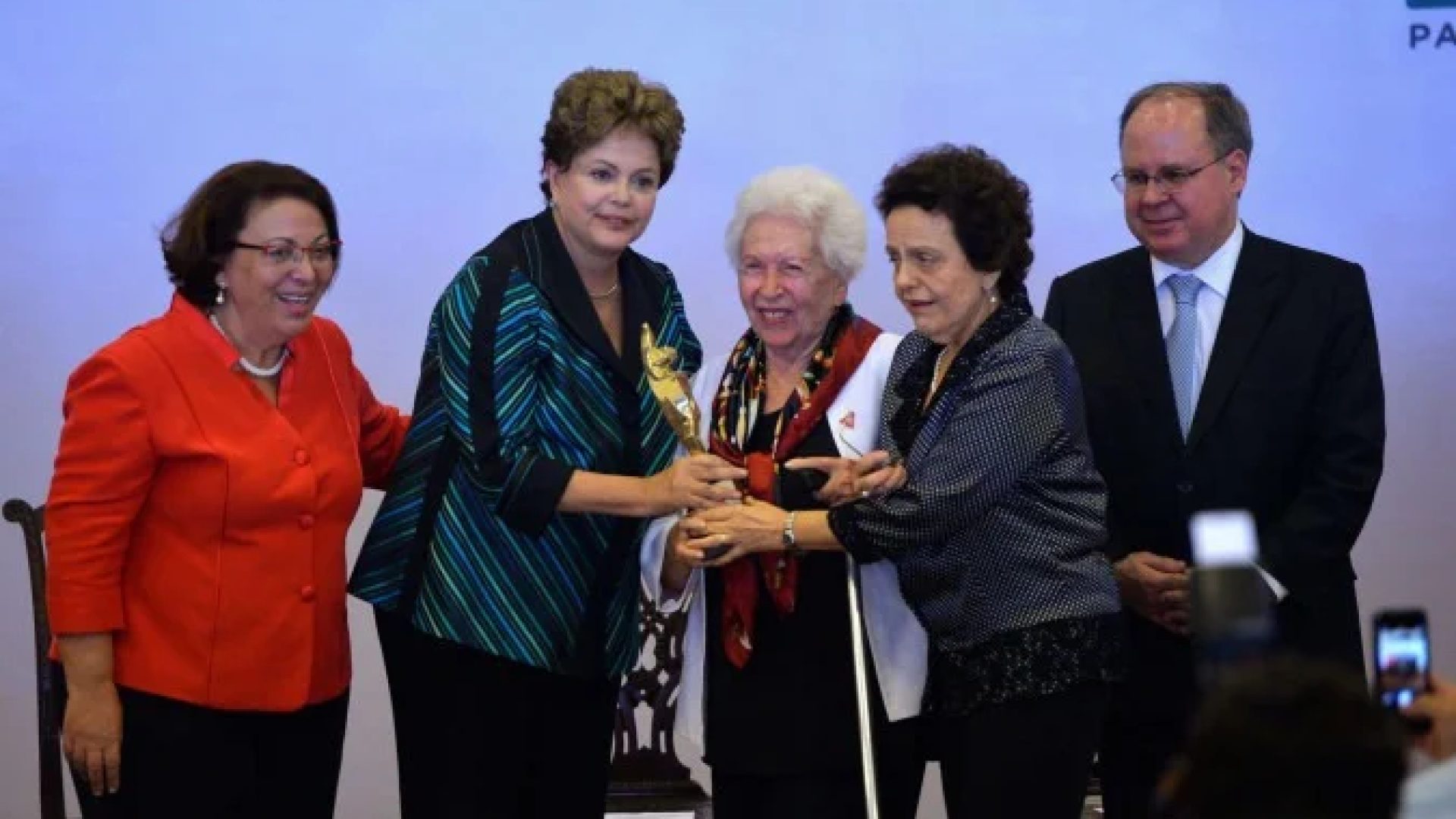 Clara entre a ex-presidente Dilma Rousseff e a ex-ministra Eleonora Menicucci ao ser premiada, em 2014 -  (crédito: Wilson Dias/Agência Brasil)