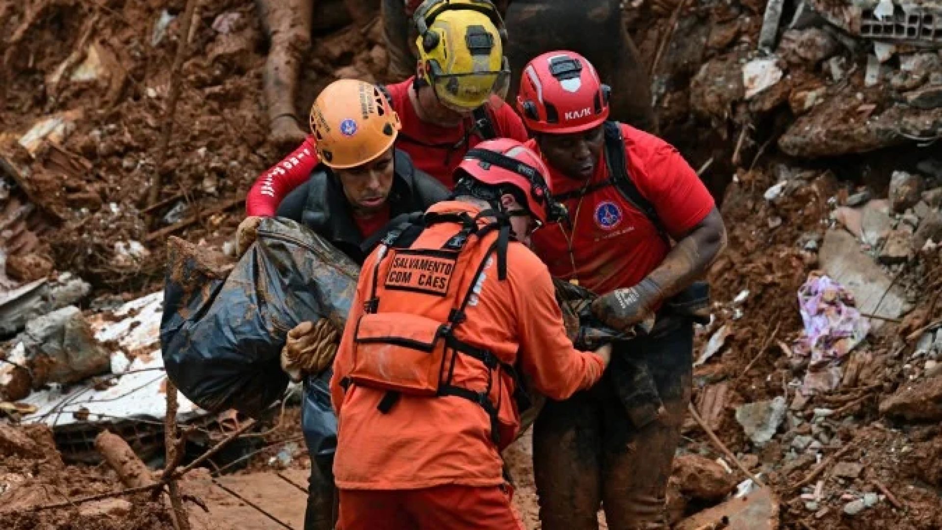Bombeiros carregam um corpo encontrado em meio aos escombros após um deslizamento de terra causado pelas fortes chuvas no bairro Parque Jardim Burnier, em Juiz de Fora, estado de Minas Gerais, em 24 de fevereiro de 2026.       -  (crédito: PABLO PORCIUNCULA / AFP)