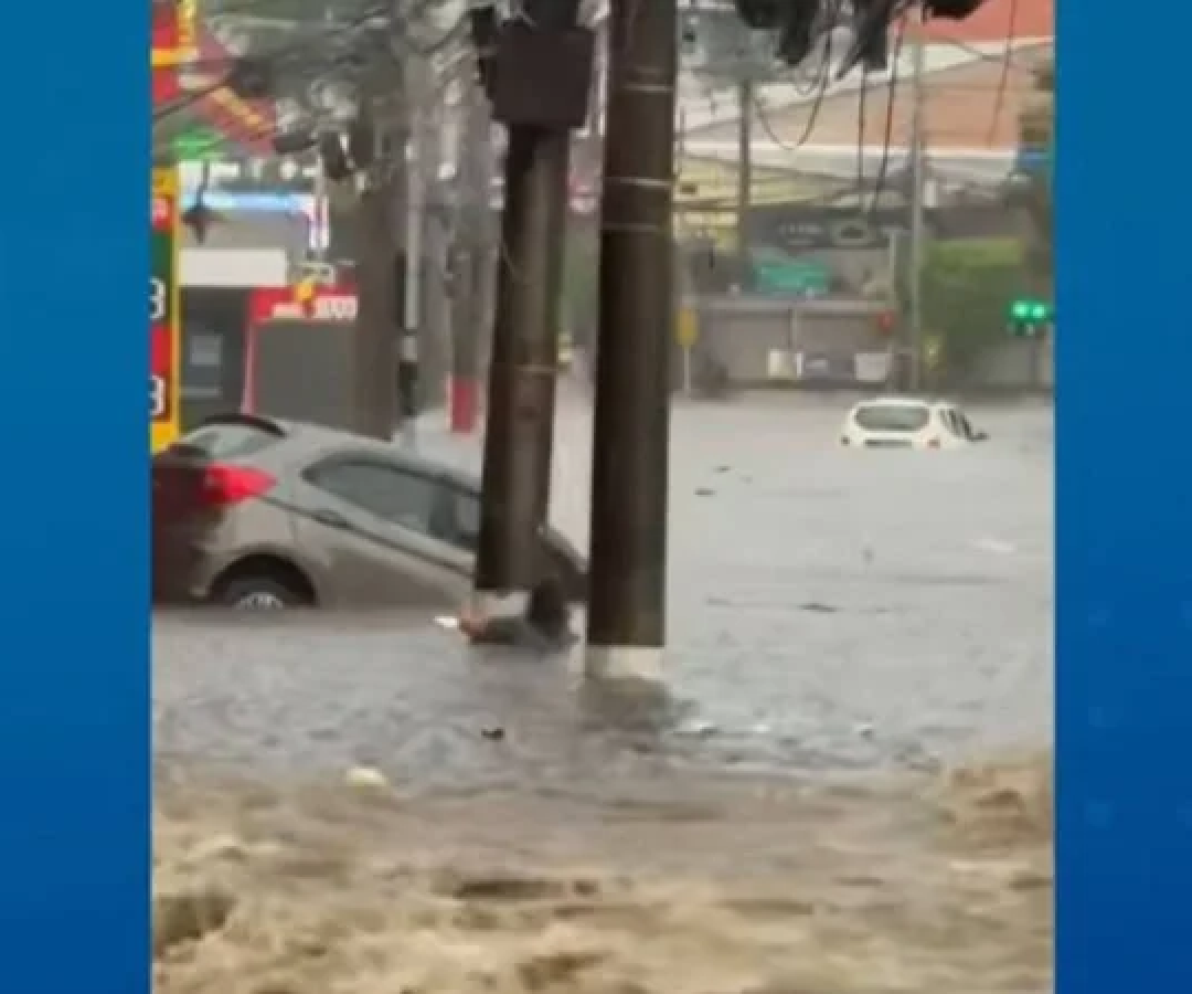 A mulher de 60 anos agarrada em um poste antes de ser arrastada pela enxurrada durante o temporal -  (crédito:  ReproduÃ§Ã£o / TV Band)