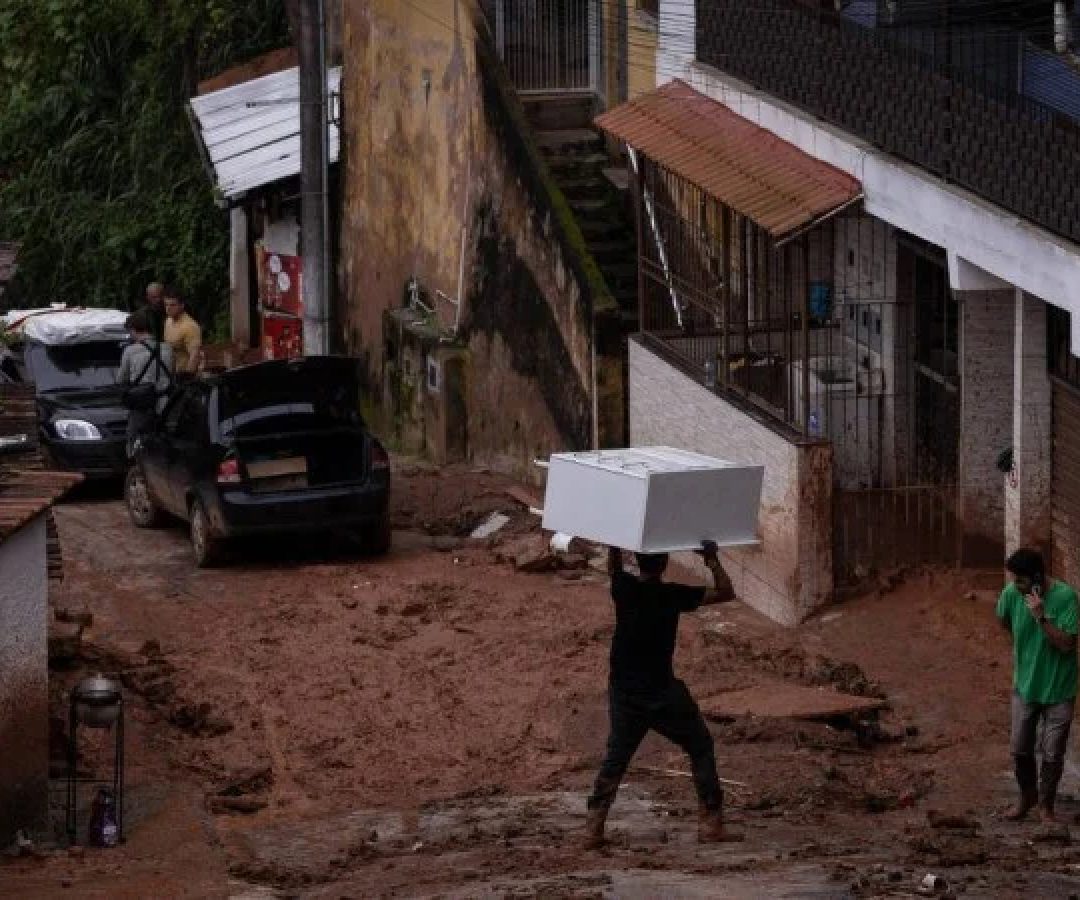 Morador carrega móvel na cabeça em rua enlameada de Juiz de Fora (MG), cidade atormentada pelas chuvas fortes há dias -  (crédito: Eduardo Anizelli/Folhapress)