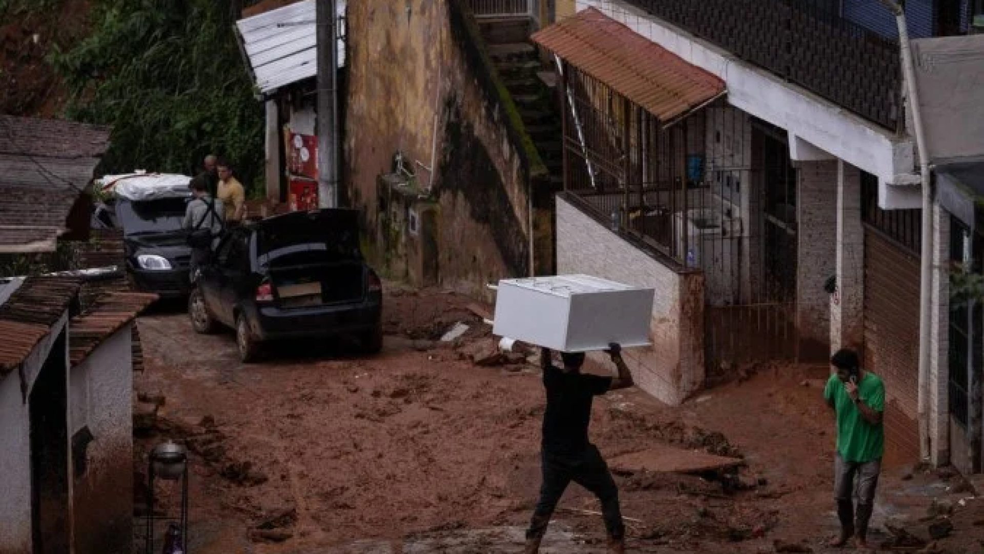 Morador carrega móvel na cabeça em rua enlameada de Juiz de Fora (MG), cidade atormentada pelas chuvas fortes há dias -  (crédito: Eduardo Anizelli/Folhapress)