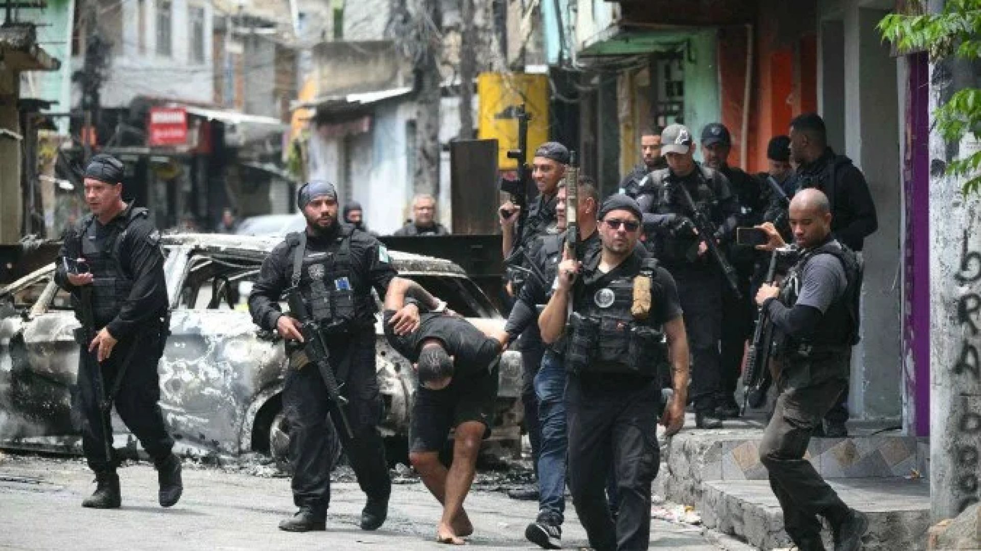 Policiais escoltam um suspeito preso durante a Operação Contenção para fora da favela Vila Cruzeiro, no complexo da Penha, no Rio de Janeiro, Brasil, em 28 de outubro de 2025       -  (crédito: MAURO PIMENTEL / AFP)