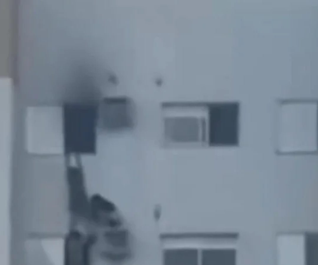 Mulher foi vista pendurada no suporte de ar-condicionado enquanto salvava mãe e sobrinha de incêndio -  (crédito: Reprodução:X)