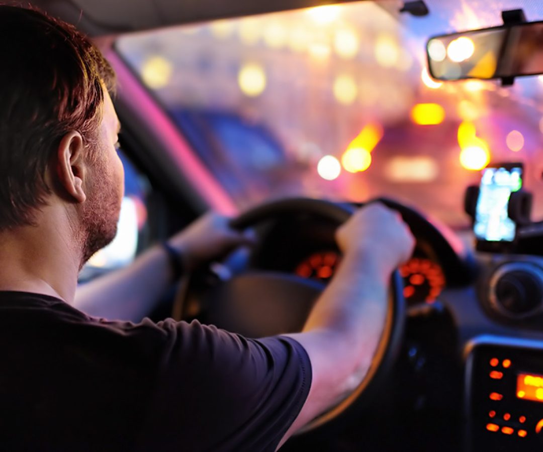 Motorista masculino dirige um carro durante o engarrafamento da noite. Vista interior.