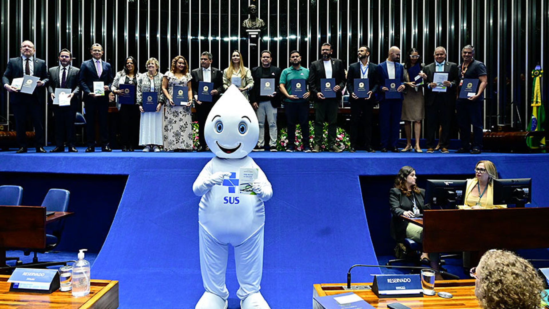 Zé Gotinha posa para foto com parlamentares e convidados.