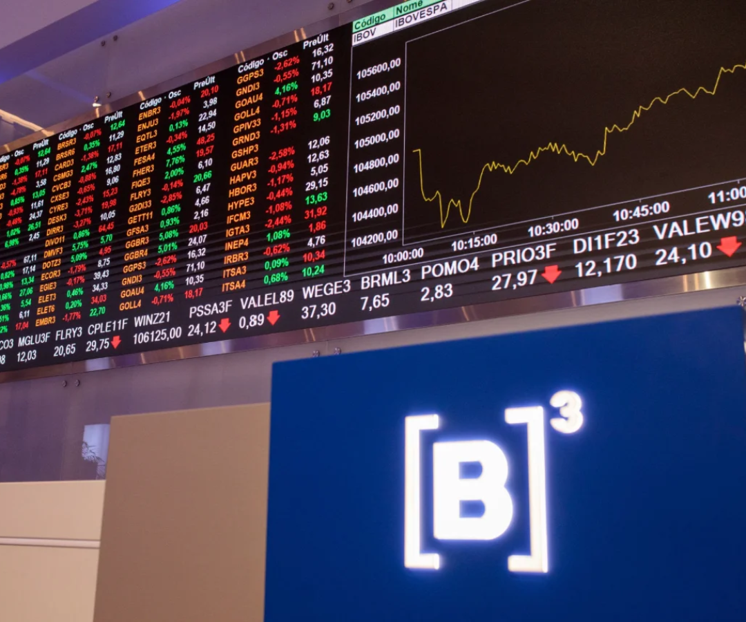 Painel eletrônico da Bolsa de Valores (B3) exibindo cotações de ações e gráficos de variação de preços em tempo real com o logotipo azul da B3 em destaque. Painel de negociações da B3, em São Paulo: movimentação de ações e anúncios corporativos ganham destaque no mercado nacional.