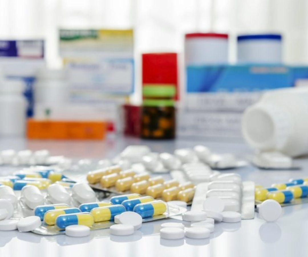 Remédios variados (cápsulas, comprimidos, embalagens) em cima de uma mesa
