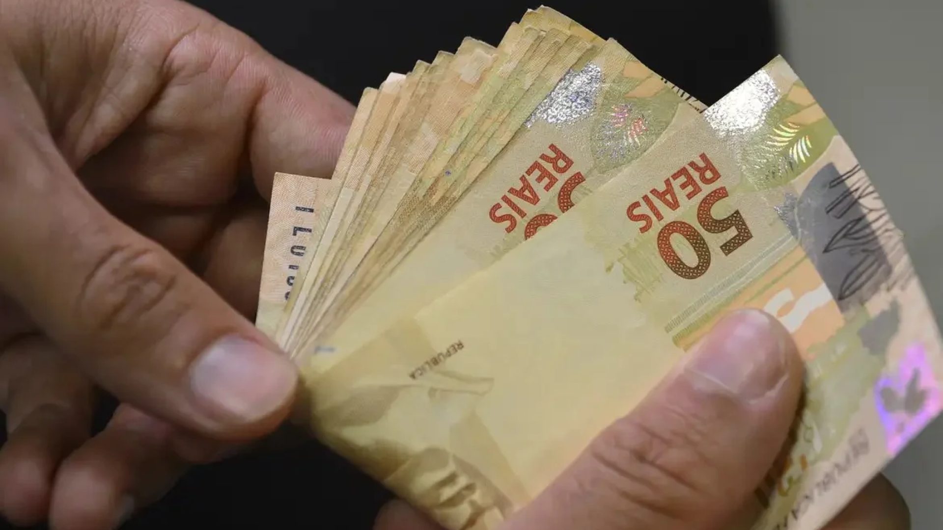 Fotografia para ilustrar matérias sobre empréstimos. Empilhamento de cédulas de real e moedas brasileiras ao lado de um capacete de proteção da construção civil e gráficos de crescimento financeiro. Proventos em construção: Com projeção de dividend yield de até 10,4%, o segmento de habitação popular ganha a preferência de analistas para a geração de caixa em agosto. Carteiras recomendadas: Com até 10,4% em dividendos Empiricus substitui Cyrela por Direcional