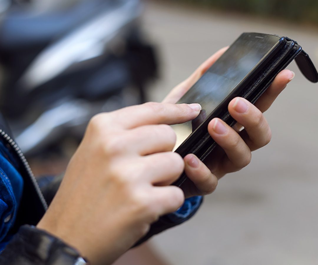 Jovem mulher usando seu celular na rua.