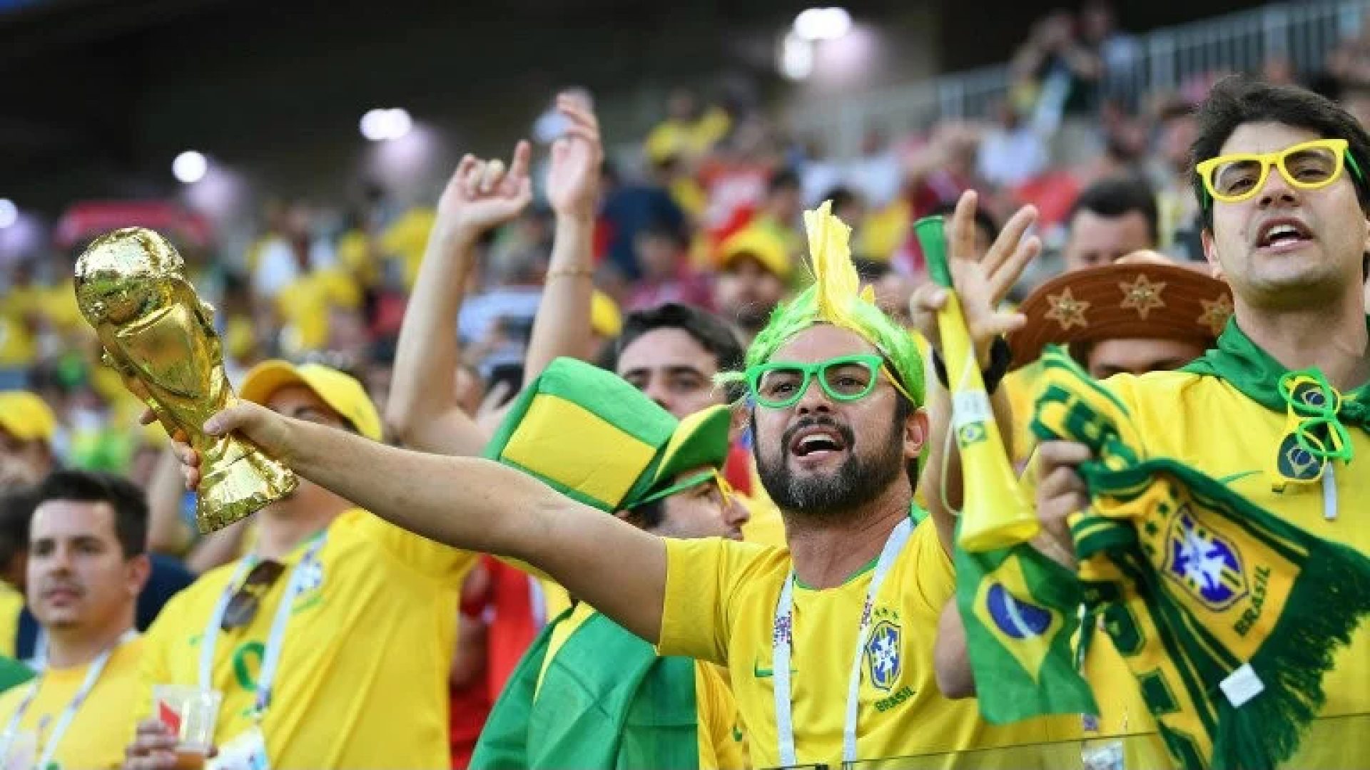 Torcedores brasileiros na arquibancada do estádio se preparam para acompanhar o jogo